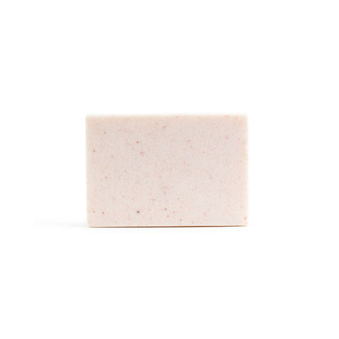 A bare, light pink handmade bar of soap on the white background.