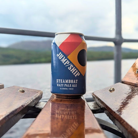 Can of Jump Ship Steamboat Hazy Pale Ale on a wooden bench with a scenic background