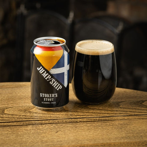 Can and glass of 'Jump Ship Stoker's Stout' on a wooden surface.