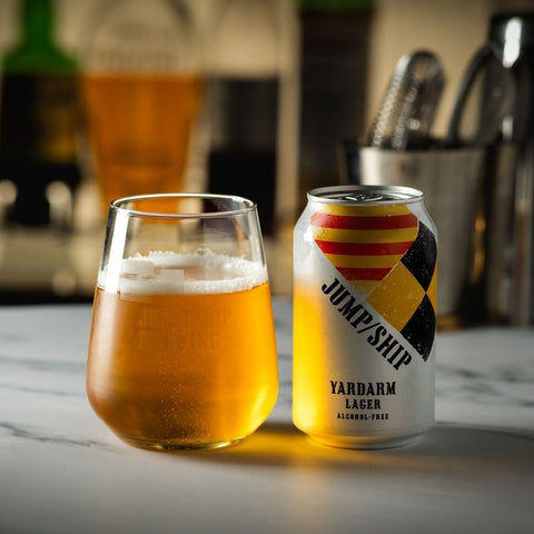 Glass and can of 'Jump Ship Yardarm Lager' on a marble surface.